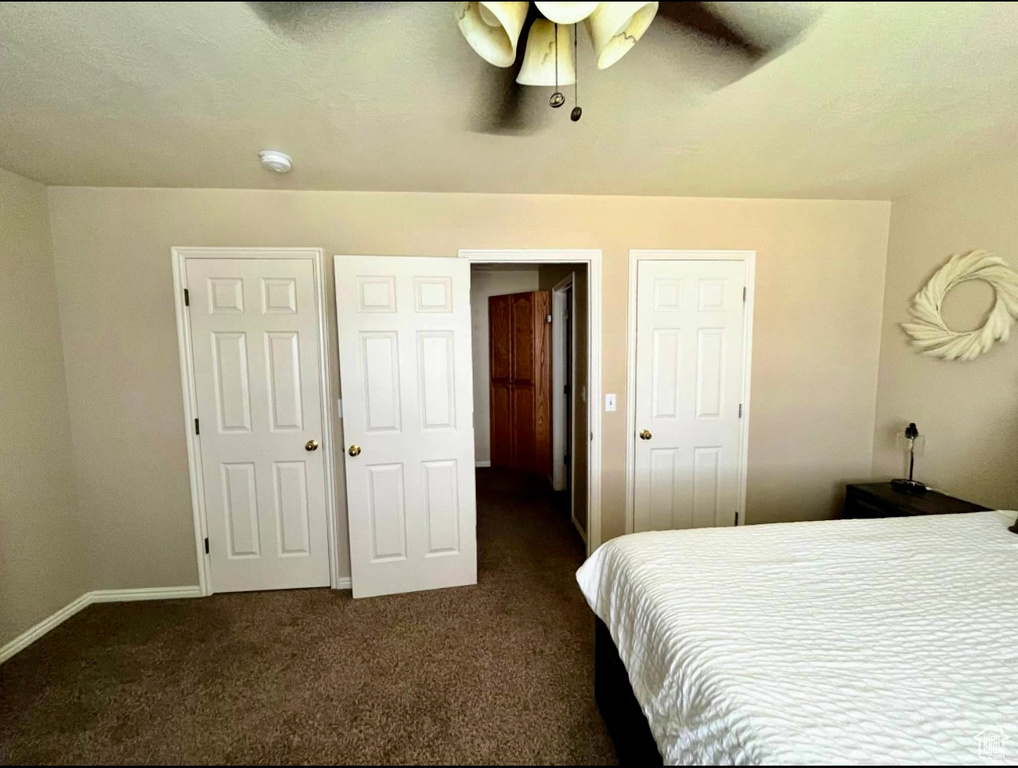 Bedroom featuring ceiling fan, dark colored carpet, and baseboards