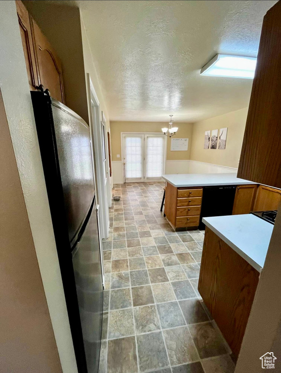 Kitchen featuring brown cabinets, a peninsula, light countertops, and freestanding refrigerator