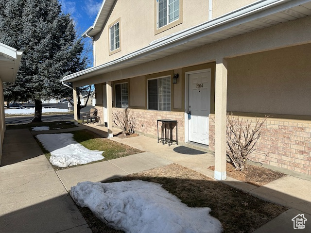 Entrance to property featuring covered porch and stucco siding