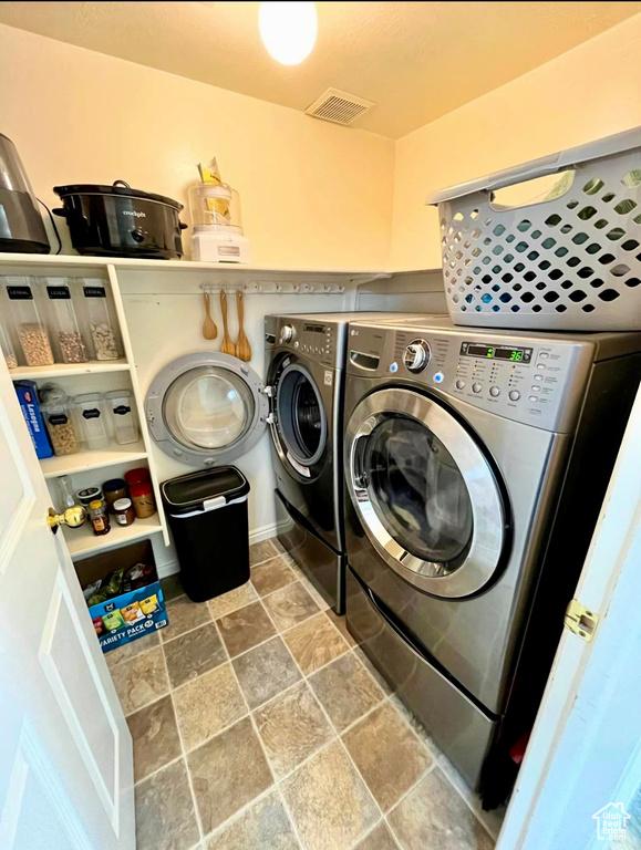 Clothes washing area with laundry area, stone finish floor, visible vents, and washer and dryer