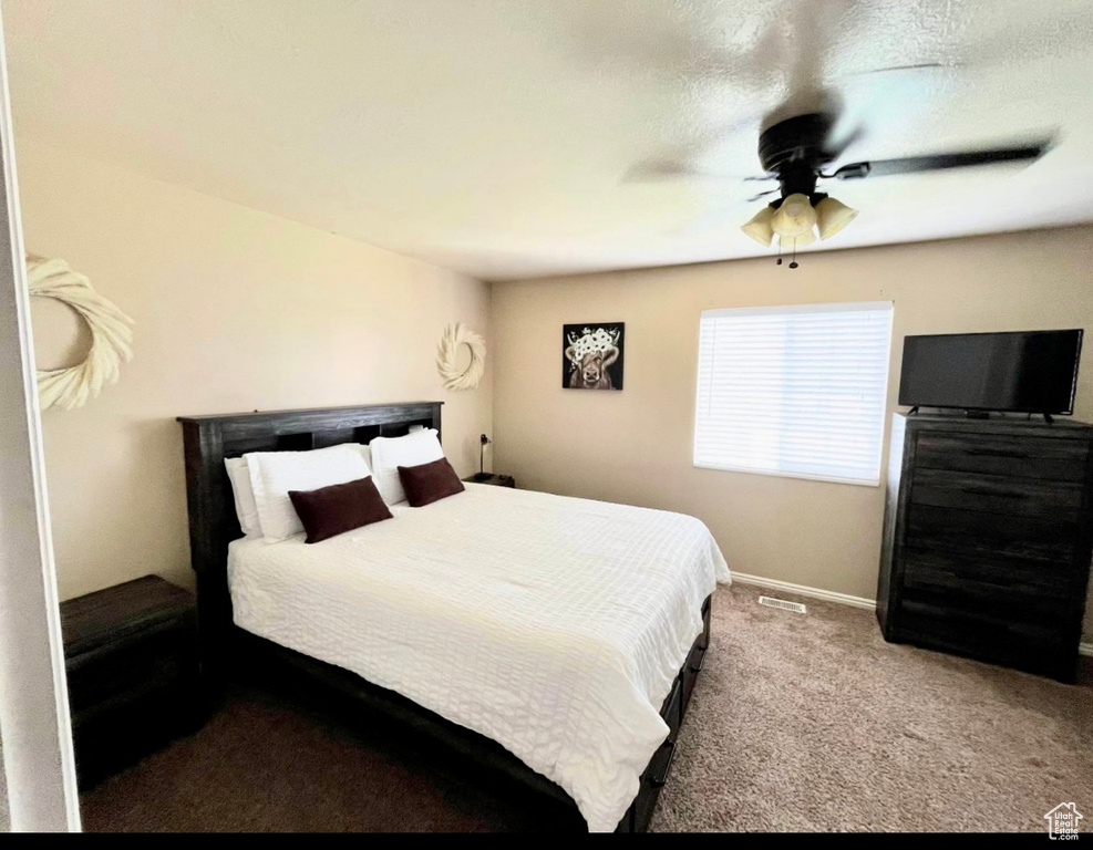 Carpeted bedroom with ceiling fan and baseboards