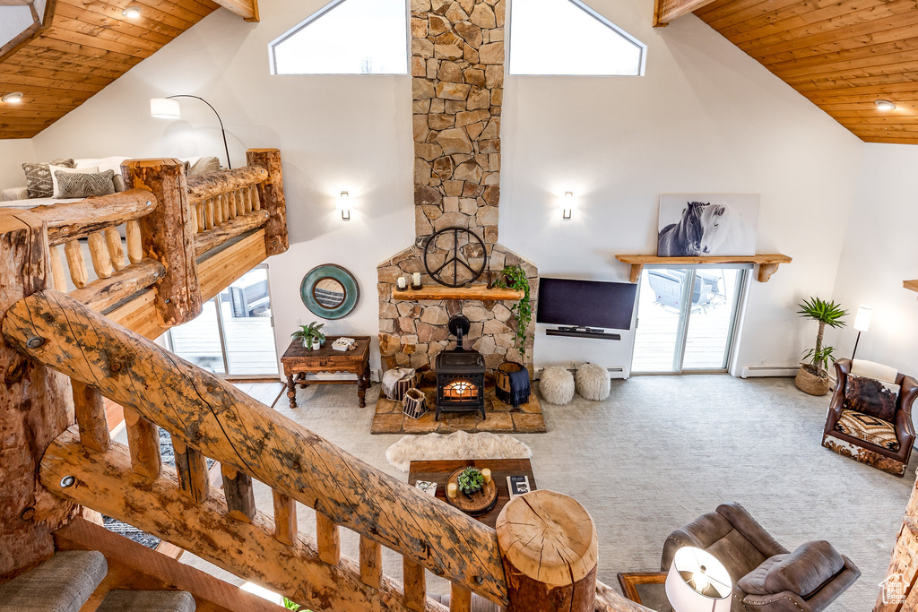 Living area with high vaulted ceiling, a healthy amount of sunlight, wood ceiling, and a wood stove