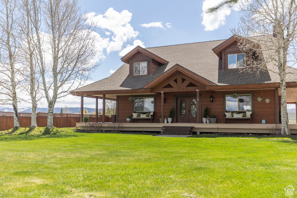 View of front of house featuring fence, a deck, a shingled roof, and a front lawn