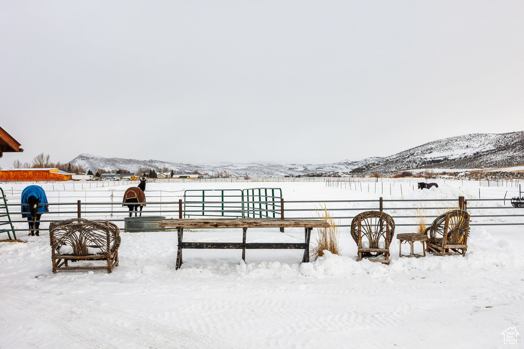Snowy yard featuring a mountain view and fence
