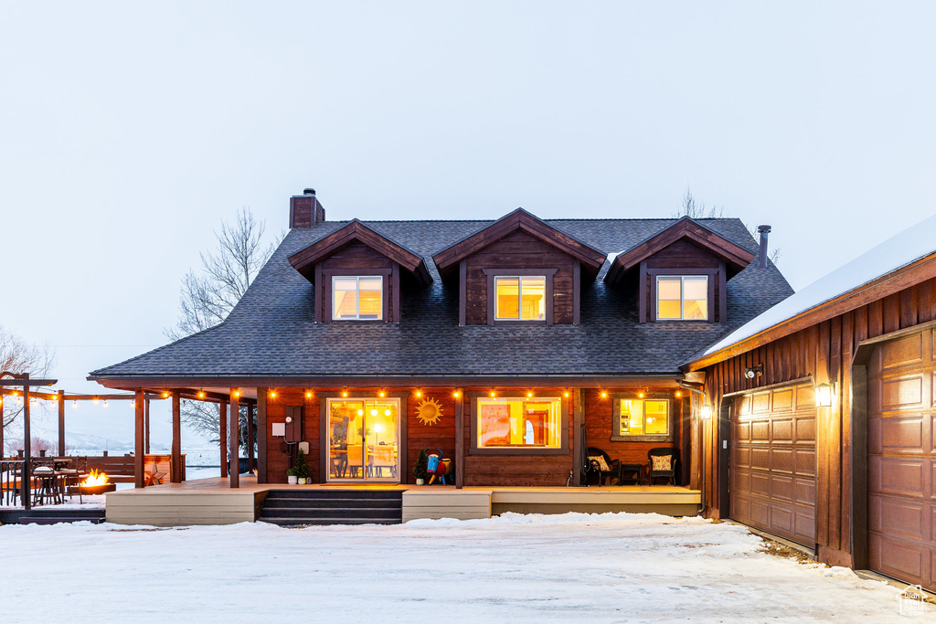 View of front of house featuring a shingled roof, covered porch, and a chimney