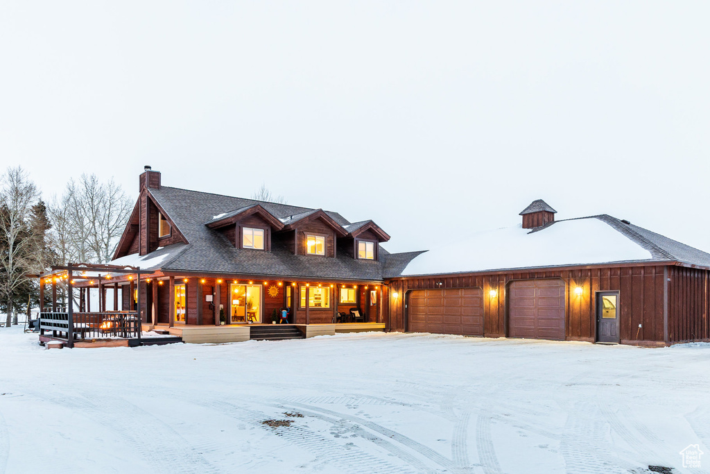 View of front of property with a porch, a garage, and a chimney
