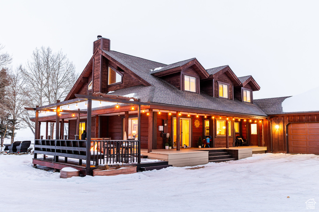 View of front of house featuring covered porch, an attached garage, and a chimney
