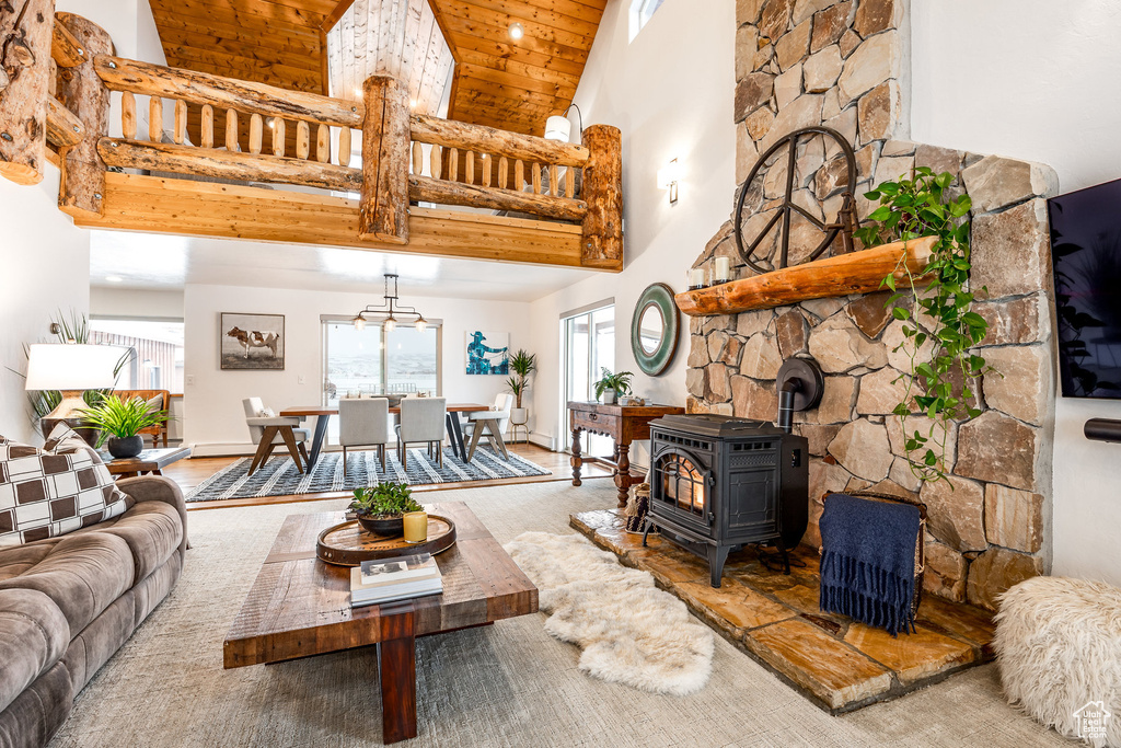 Living room with high vaulted ceiling, wood ceiling, a wood stove, and wood finished floors