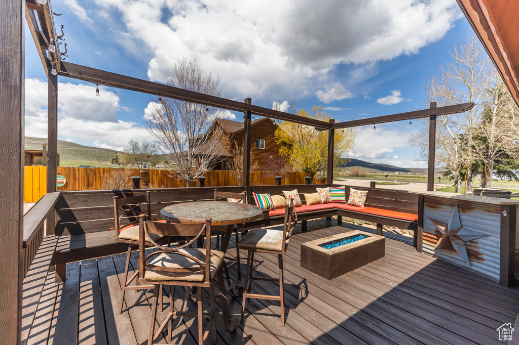 Wooden terrace with a fenced backyard and an outdoor living space with a fire pit