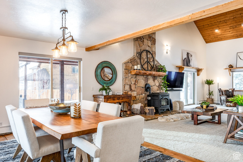 Dining space with a wood stove, wood finished floors, and vaulted ceiling