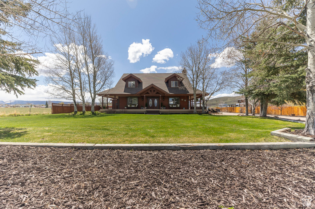 View of front of house featuring a porch, fence, a chimney, and a front yard