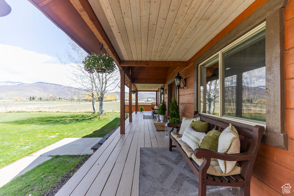 Wooden terrace featuring a lawn and a mountain view