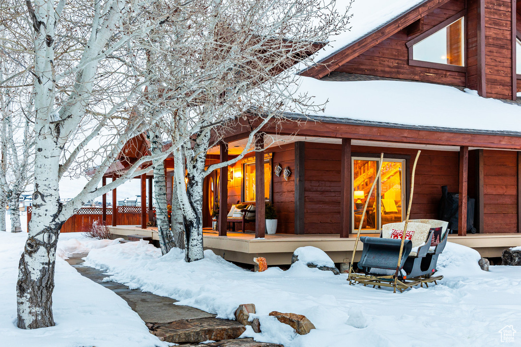 Snow covered rear of property featuring a porch