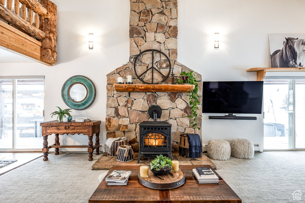 Living room with a healthy amount of sunlight, baseboard heating, and a wood stove