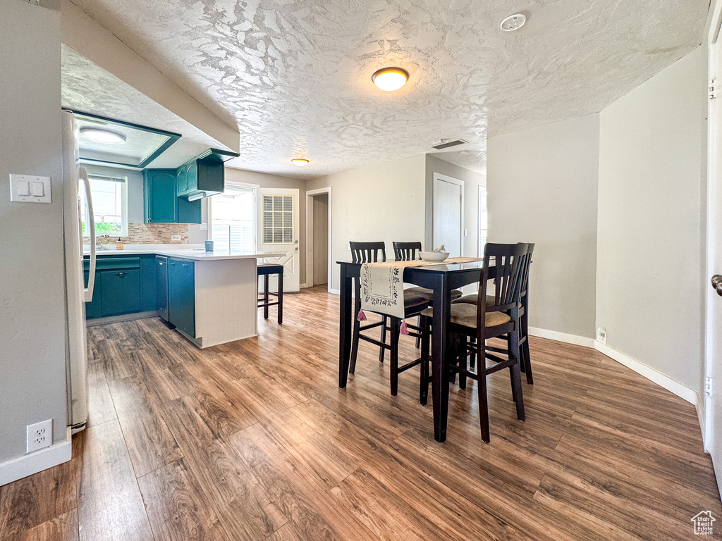 Dining room featuring dark wood-type flooring, baseboards, and a textured ceiling