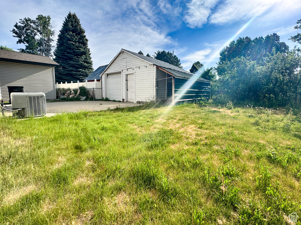 View of yard with cooling unit, a garage, an outbuilding, and driveway