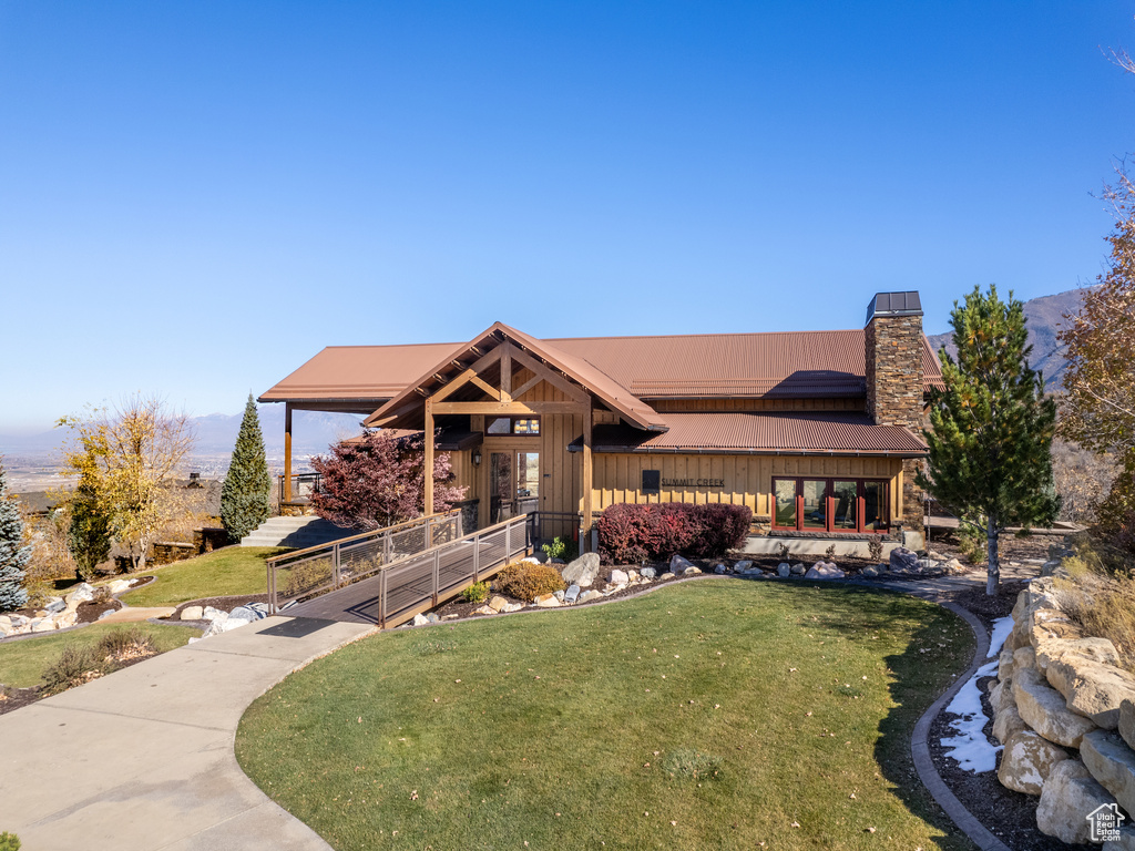 View of front of house with a front lawn, board and batten siding, and a chimney