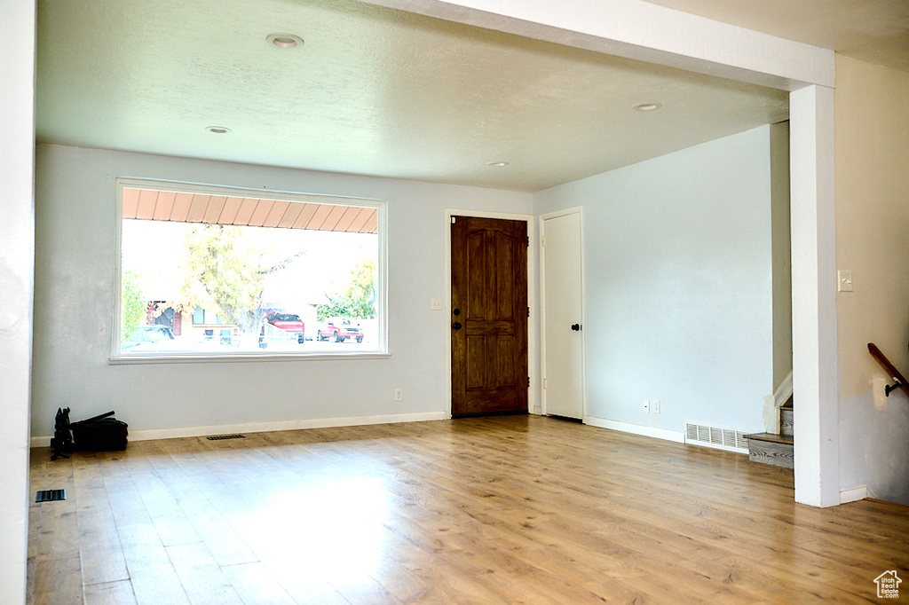 Unfurnished room featuring light wood-style flooring, visible vents, and baseboards