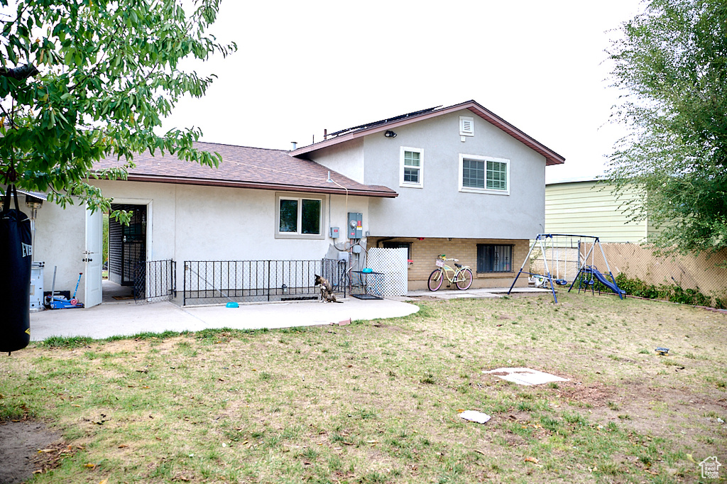 Back of house with a playground, a yard, brick siding, stucco siding, and fence