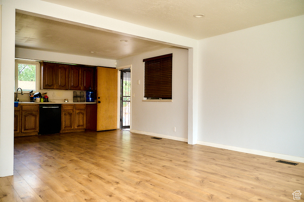 Kitchen with black dishwasher, light countertops, visible vents, light wood-style flooring, and baseboards