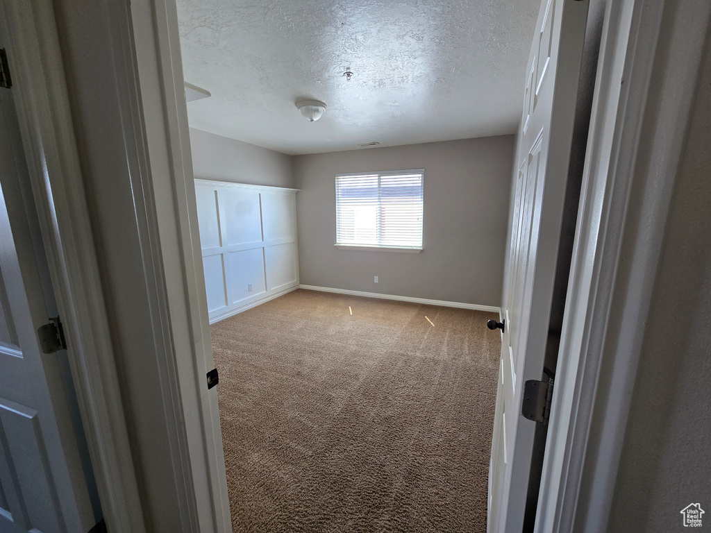Unfurnished bedroom featuring a textured ceiling, carpet flooring, baseboards, and visible vents
