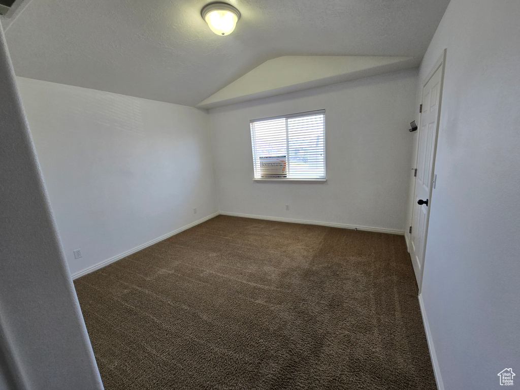 Interior space featuring baseboards, a textured ceiling, carpet, and lofted ceiling