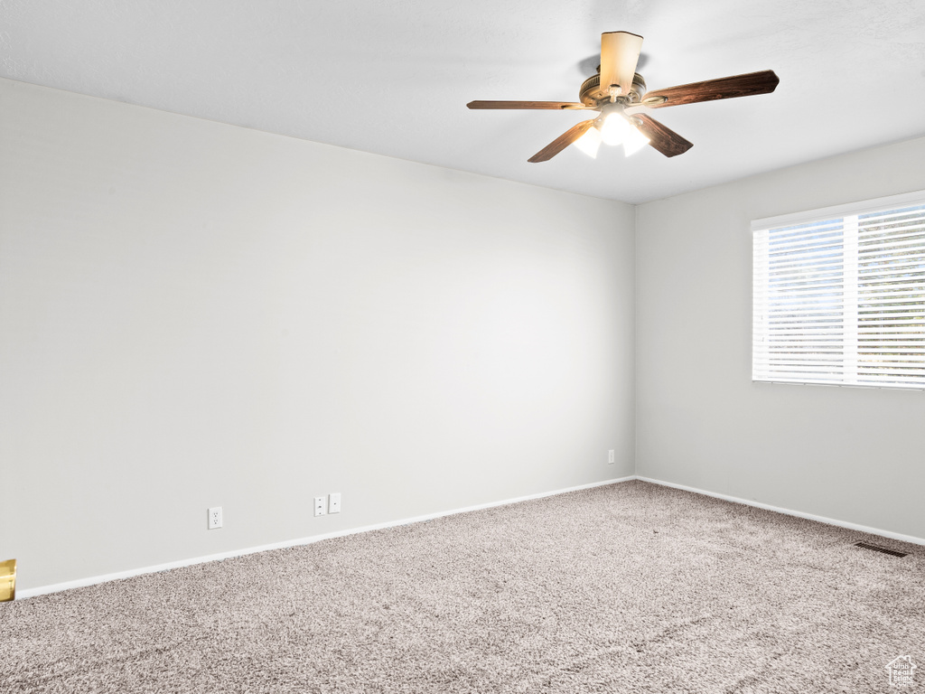 Carpeted empty room with ceiling fan and baseboards