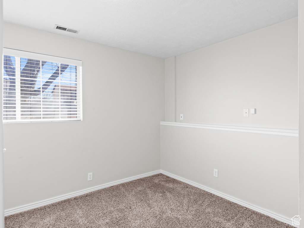 Carpeted empty room featuring visible vents and baseboards