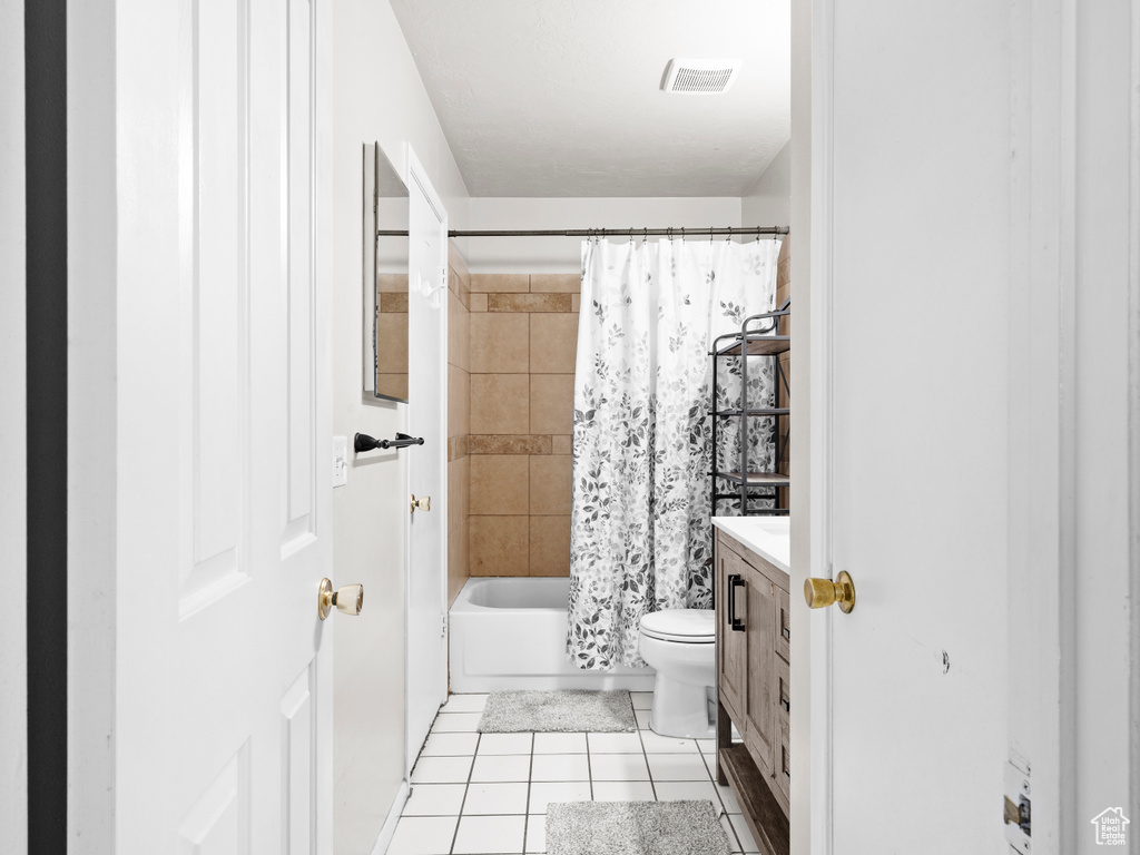 Bathroom featuring visible vents, toilet, tile patterned flooring, shower / bath combination with curtain, and vanity