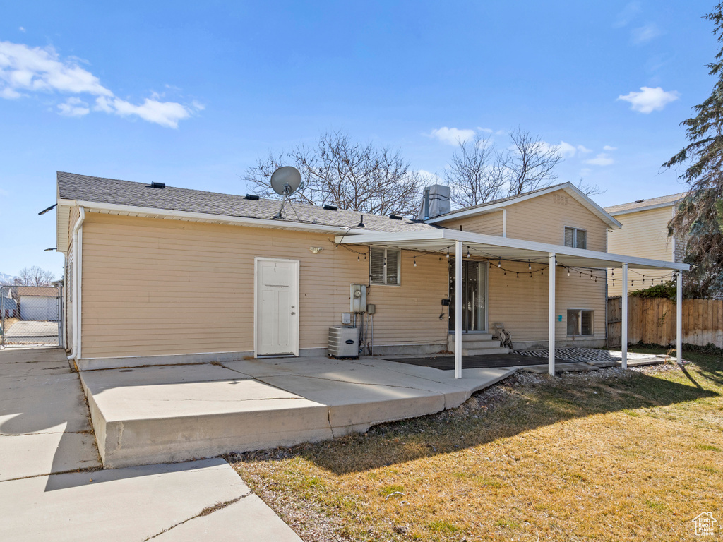 Rear view of house featuring central AC, a patio, a lawn, and fence