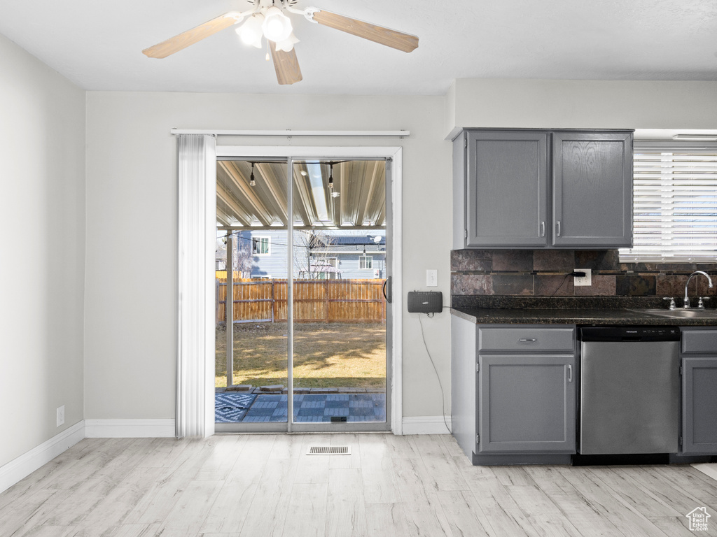 Kitchen with tasteful backsplash, dishwasher, dark countertops, gray cabinets, and a sink