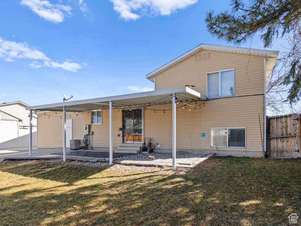 Rear view of property with entry steps, fence, a patio, and a lawn