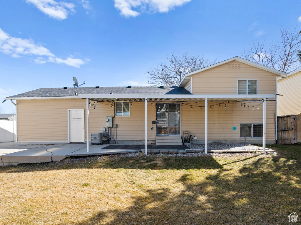 Back of property featuring a patio, a lawn, and fence