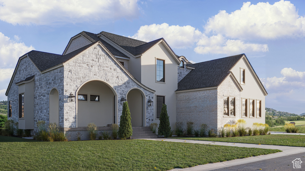 French country home featuring a front lawn and brick siding