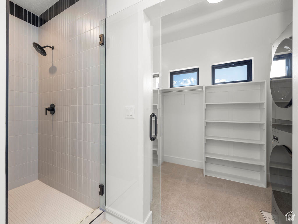 Full bath featuring a stall shower and stacked washer and clothes dryer