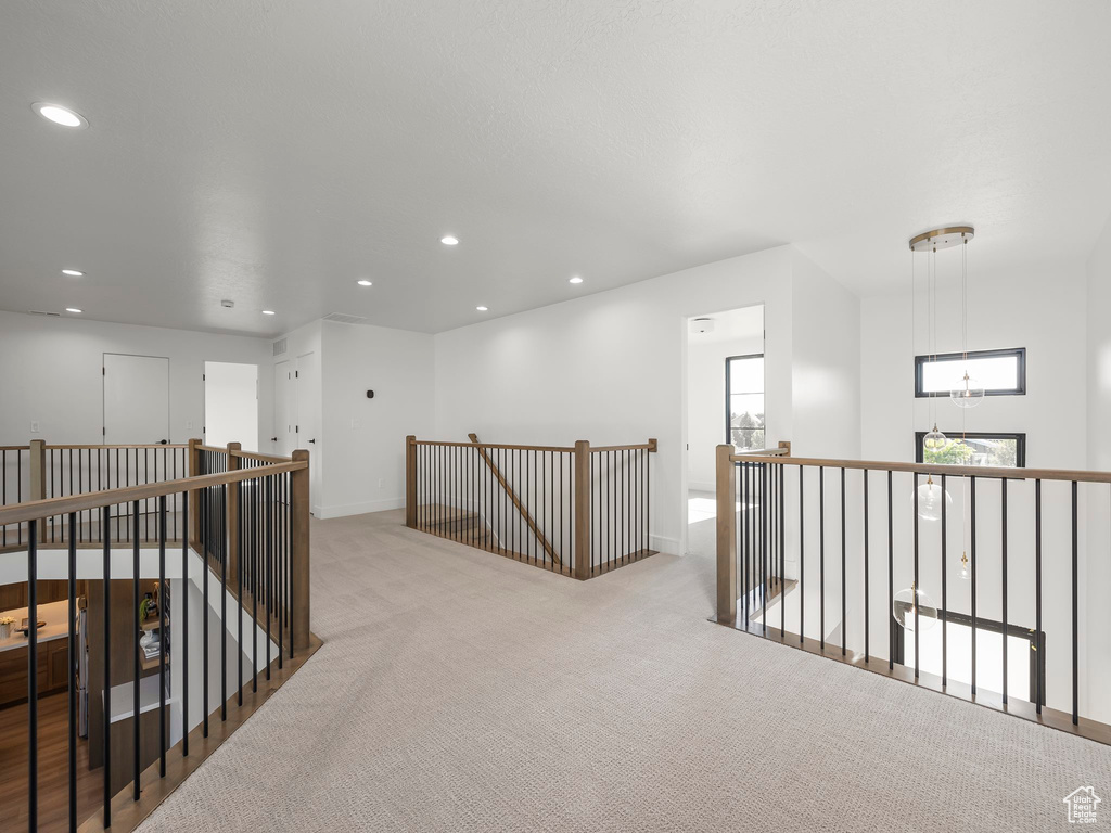 Hallway featuring recessed lighting, baseboards, light colored carpet, and an upstairs landing