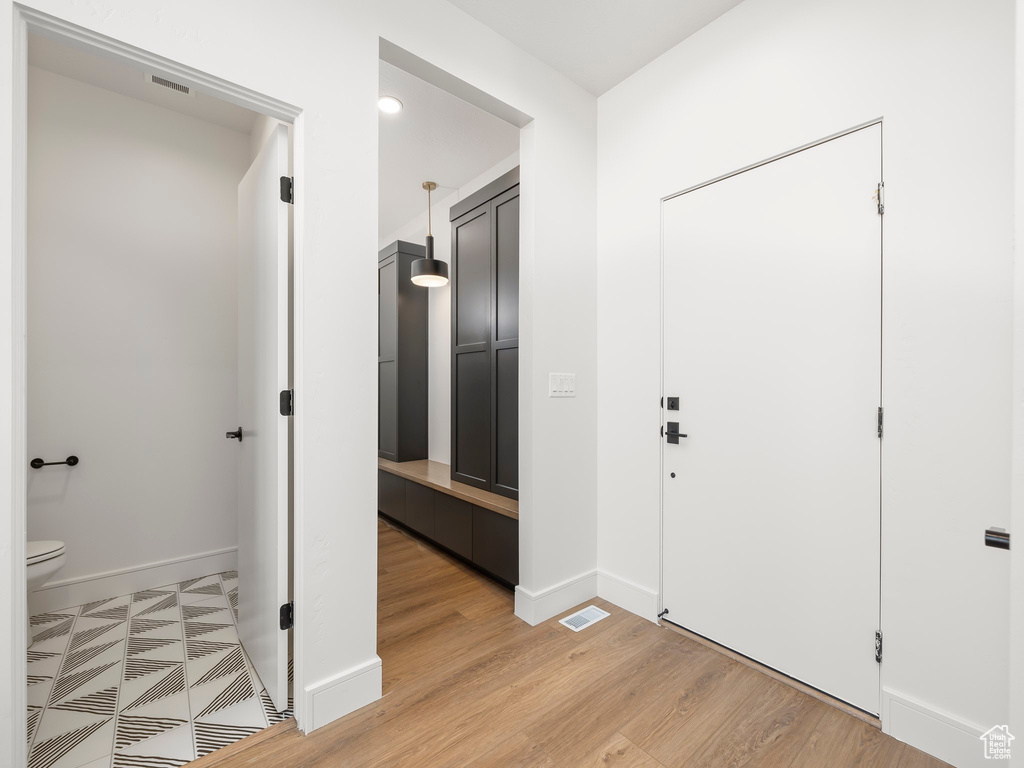 Foyer with light wood-type flooring, baseboards, and visible vents