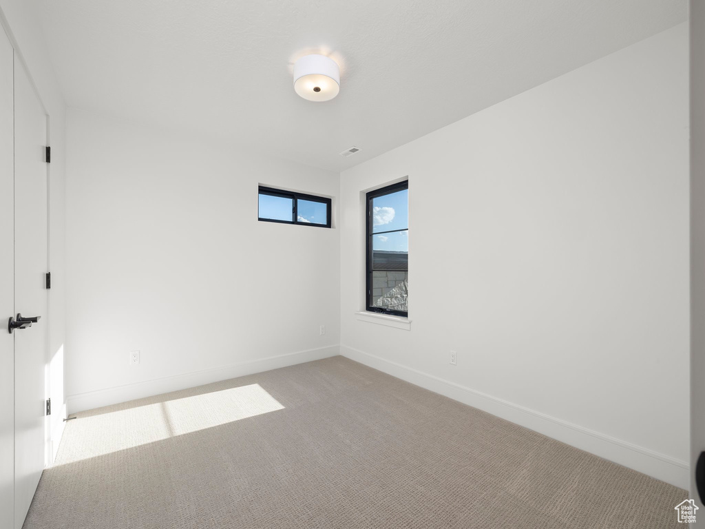 Unfurnished room with baseboards and light colored carpet