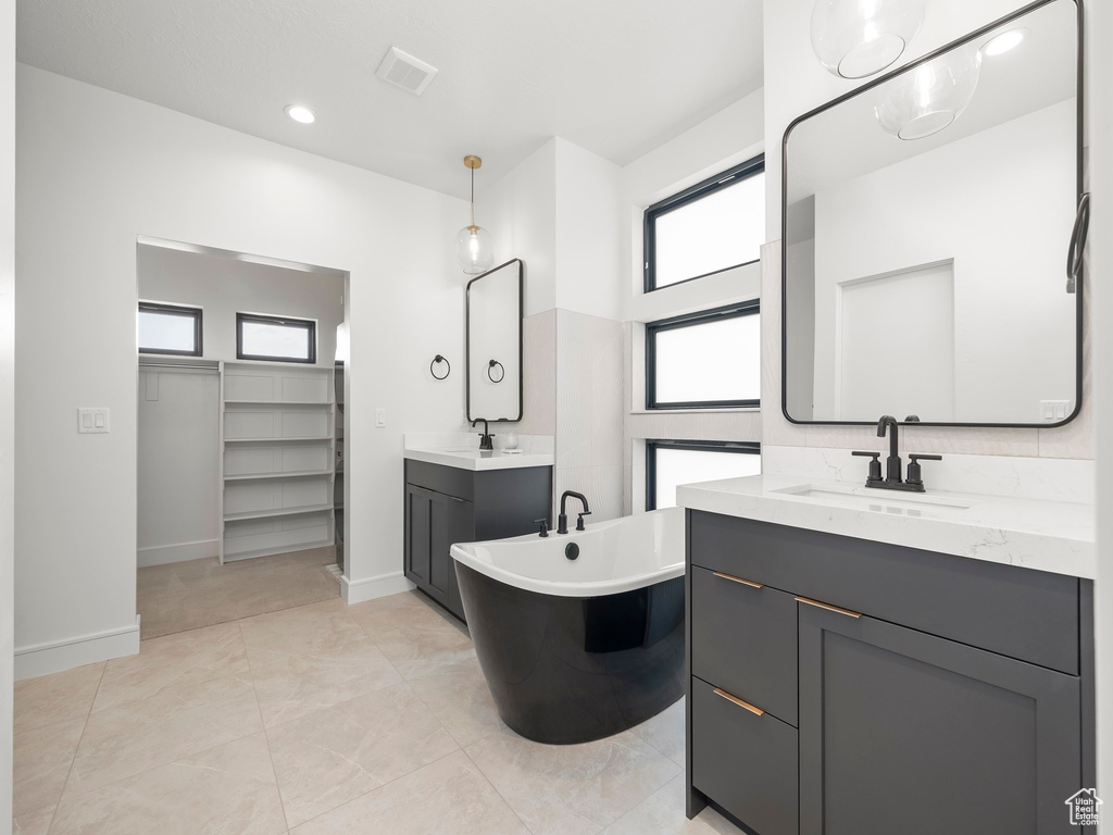 Bathroom with a freestanding tub, a sink, two vanities, visible vents, and a spacious closet