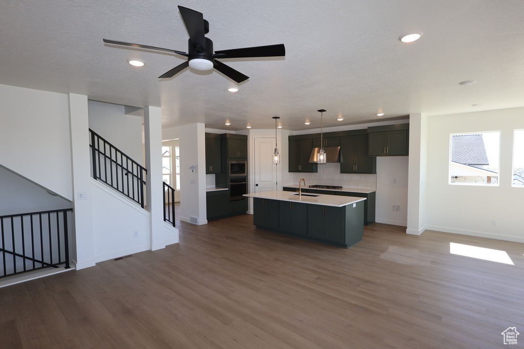 Kitchen featuring under cabinet range hood, a healthy amount of sunlight, a sink, and recessed lighting