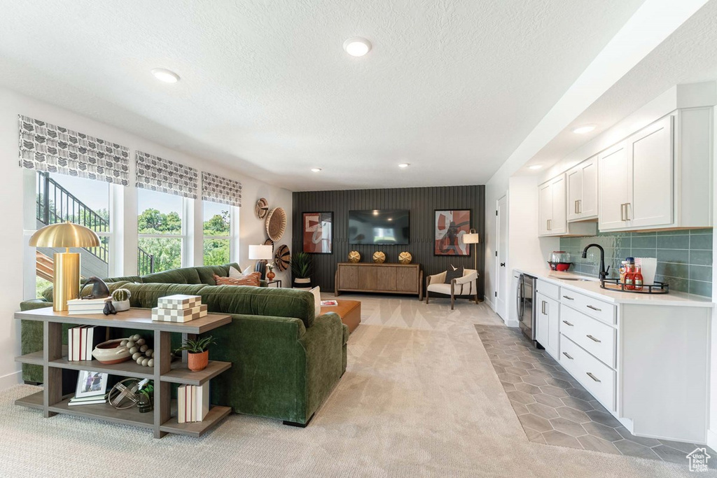 Living area with light carpet, a textured ceiling, beverage cooler, and recessed lighting
