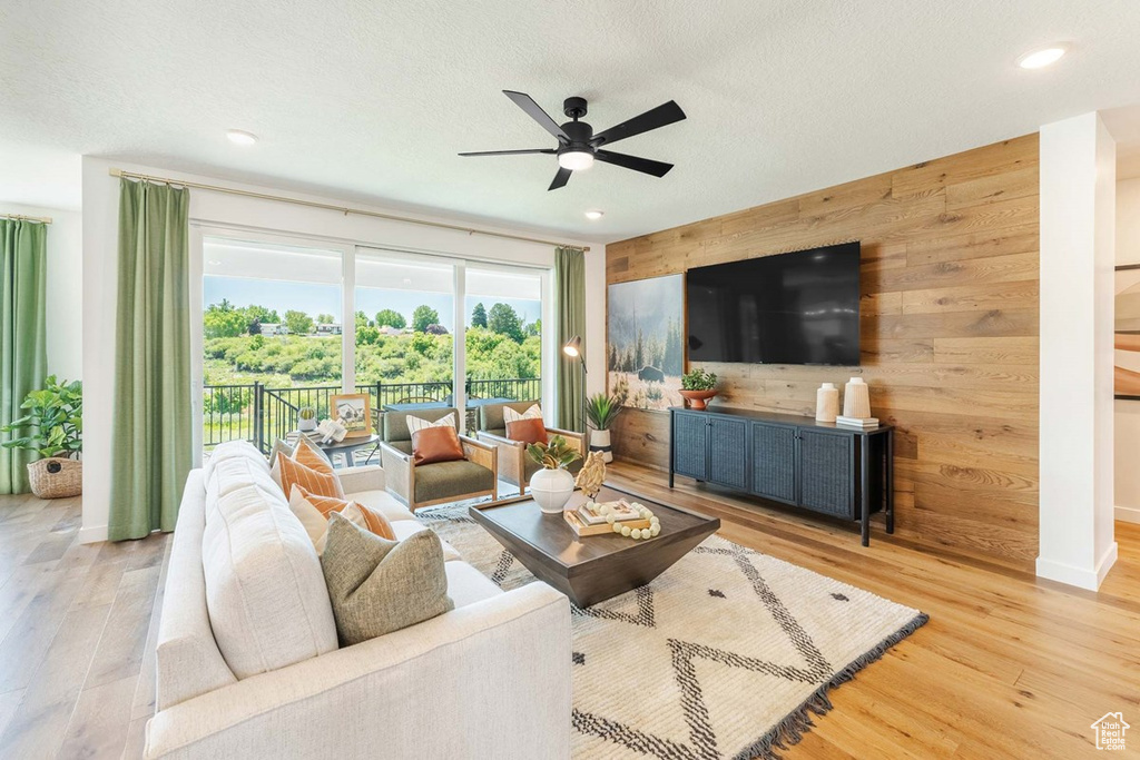 Living room featuring wooden walls, wood finished floors, recessed lighting, and a ceiling fan