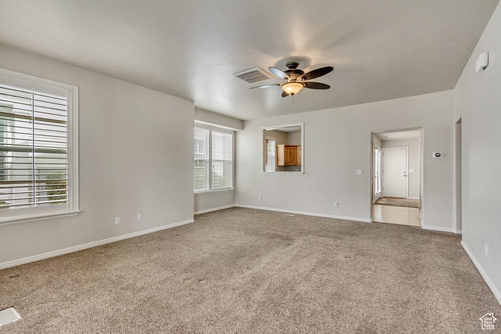 Unfurnished room featuring a ceiling fan, carpet flooring, visible vents, and baseboards