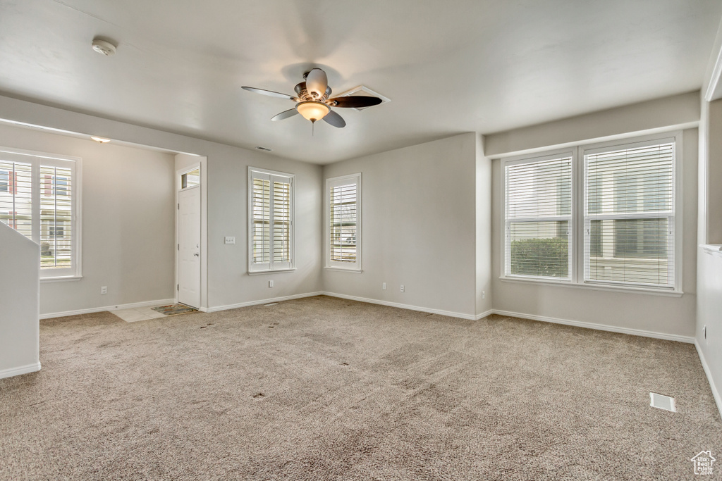 Unfurnished room with a ceiling fan, a healthy amount of sunlight, light colored carpet, and baseboards