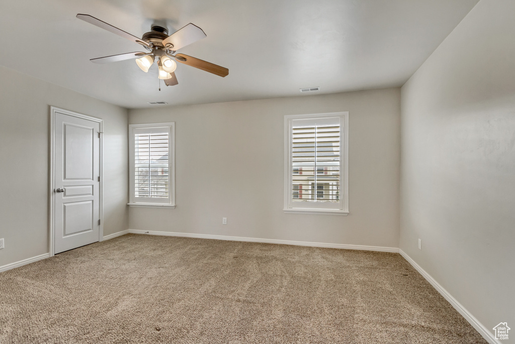 Spare room with carpet, visible vents, ceiling fan, and baseboards