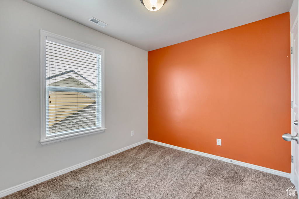 Unfurnished room featuring baseboards, visible vents, and carpet flooring
