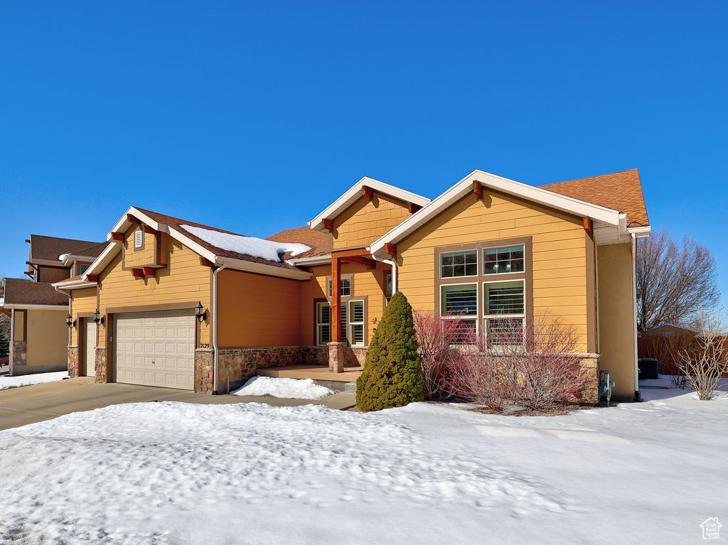 View of front of house featuring driveway, stone siding, and a garage