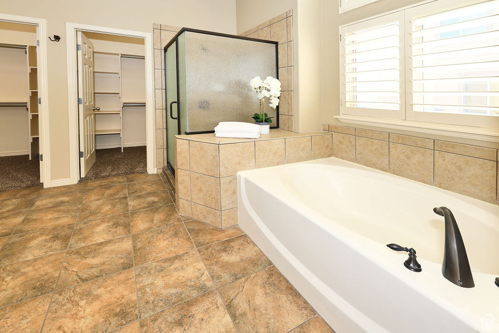 Full bath with a garden tub, a walk in closet, and a stall shower