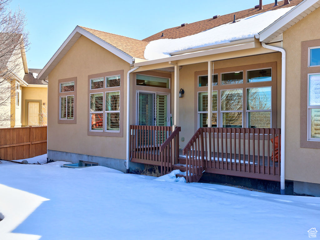 View of front of home featuring a porch, roof with shingles, fence, and stucco siding