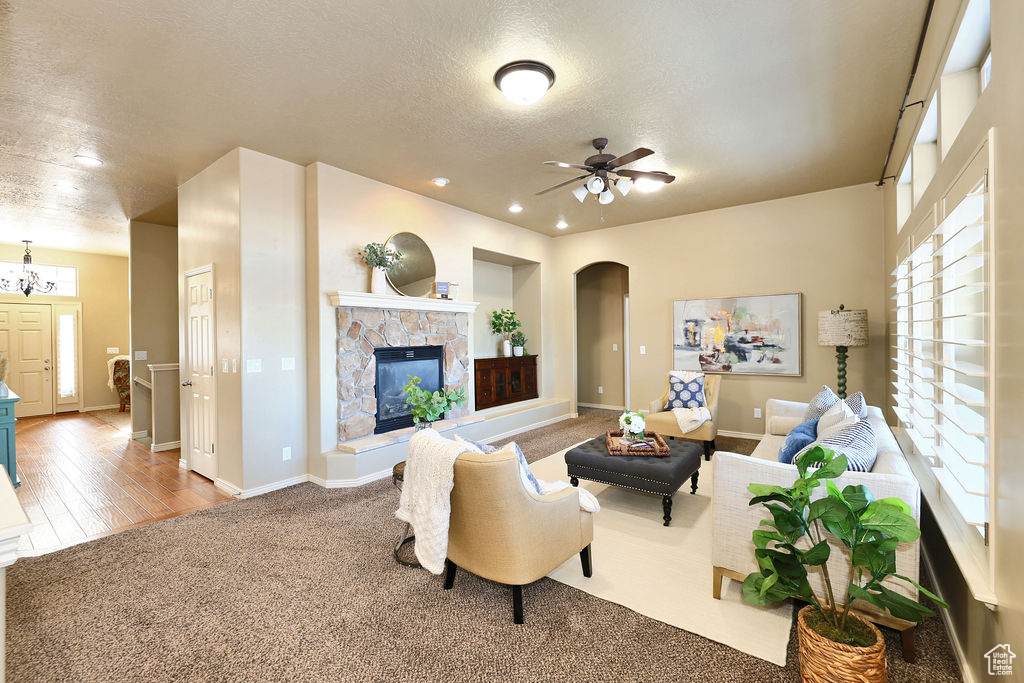 Living room with baseboards, arched walkways, ceiling fan, a textured ceiling, and a fireplace